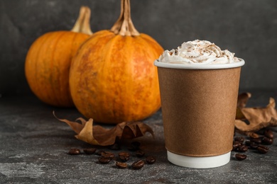 Photo of Paper cup with tasty pumpkin spice latte on grey table. Space for text