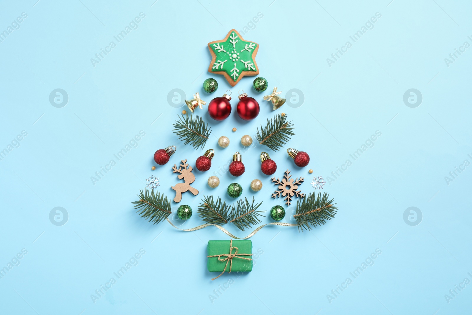 Photo of Christmas tree silhouette of fir branches and festive decoration on light blue background, flat lay