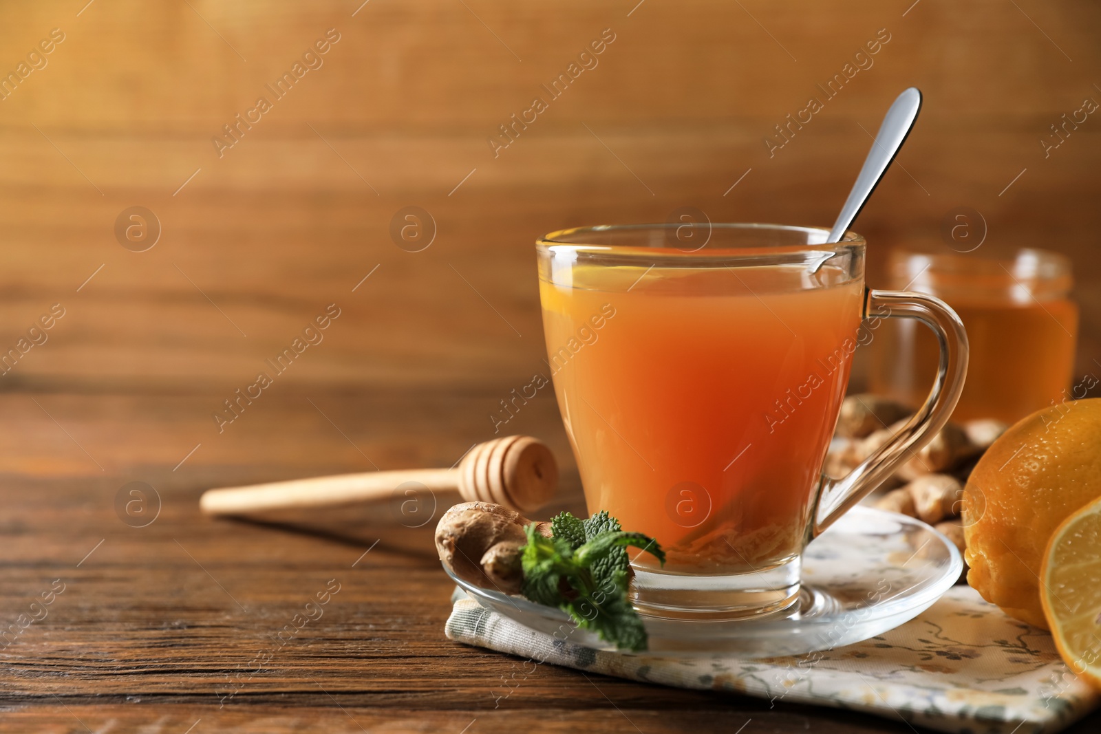 Photo of Cup of delicious ginger tea and ingredients on wooden table, space for text