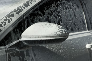 Photo of Auto with cleaning foam at outdoor car wash, closeup