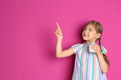 Photo of Cute little girl with glass of milk on color background