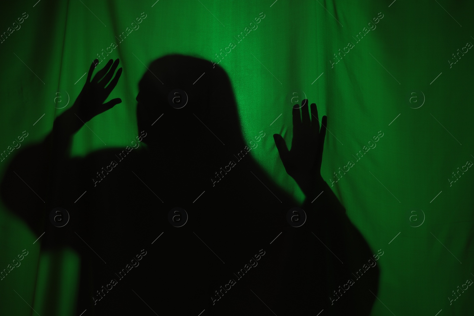 Photo of Silhouette of creepy ghost behind dark green cloth