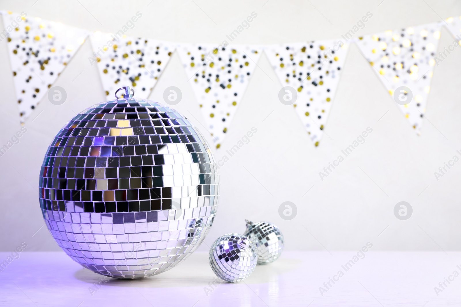 Photo of Shiny disco balls on white wooden table. Space for text