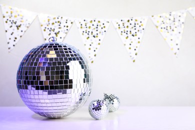 Photo of Shiny disco balls on white wooden table. Space for text