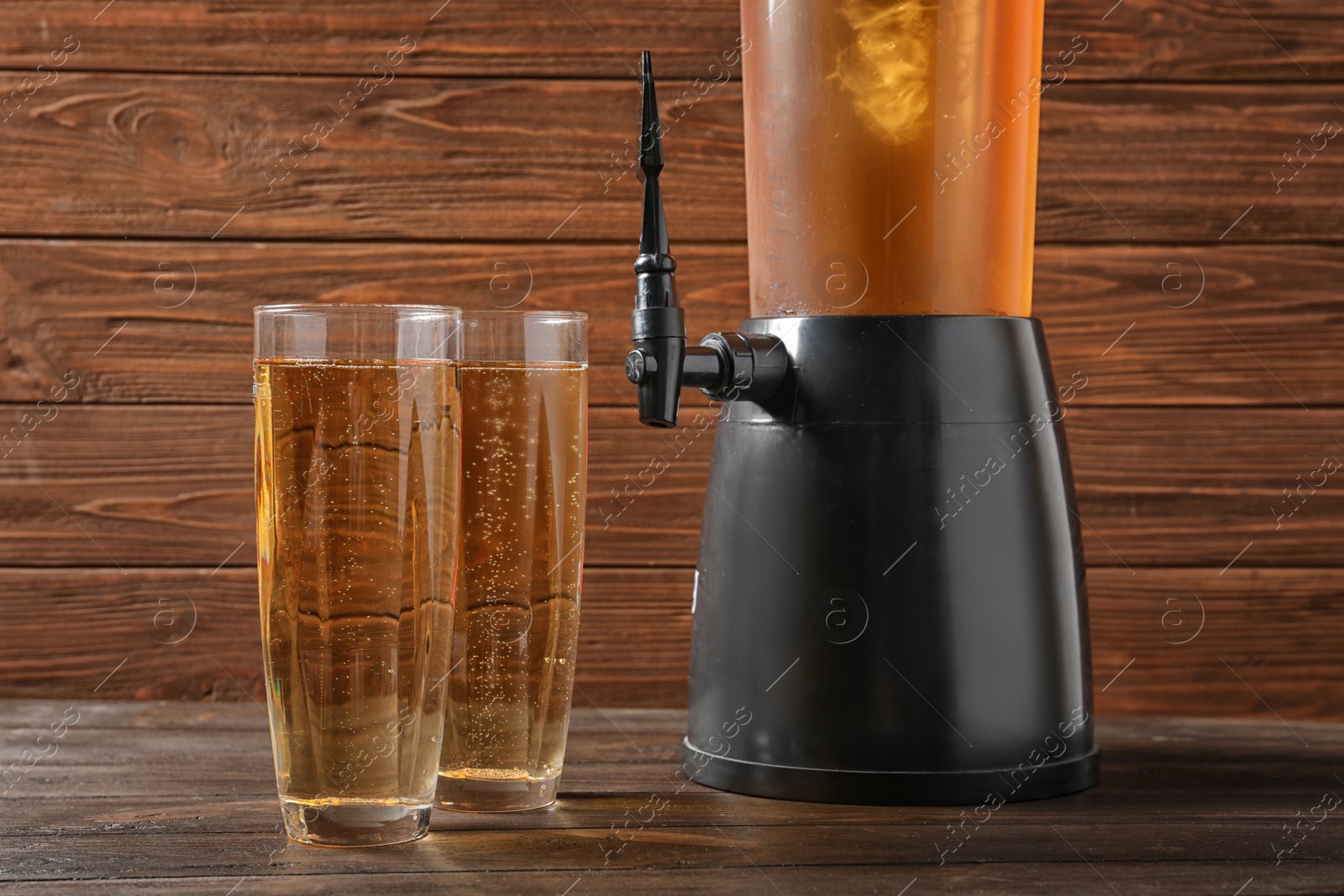 Photo of Tower dispenser and glasses with cold beer on table