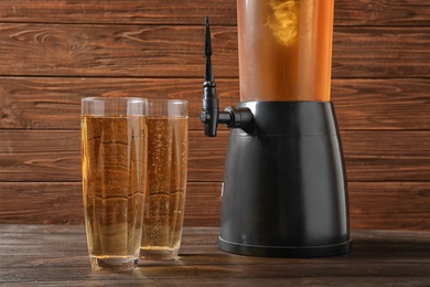 Photo of Tower dispenser and glasses with cold beer on table