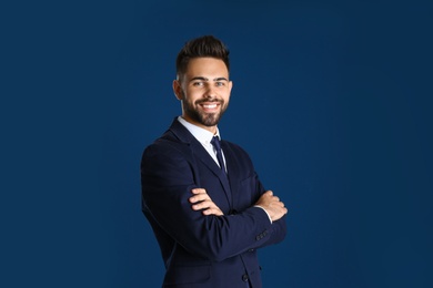 Portrait of handsome smiling man in office suit on color background