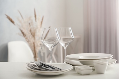 Photo of Setclean dishware, wineglasses and cutlery on white table indoors