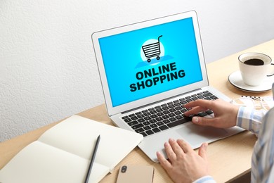 Image of Woman using laptop for online shopping at table, closeup