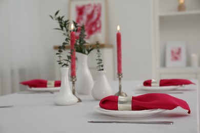 Photo of Beautiful table setting with green branches in vases and burning candles indoors. Stylish dining room