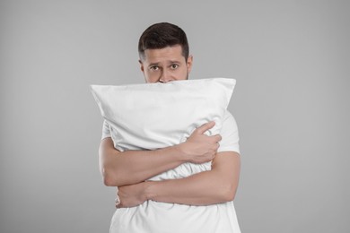 Photo of Sleepy man with pillow on grey background. Insomnia problem
