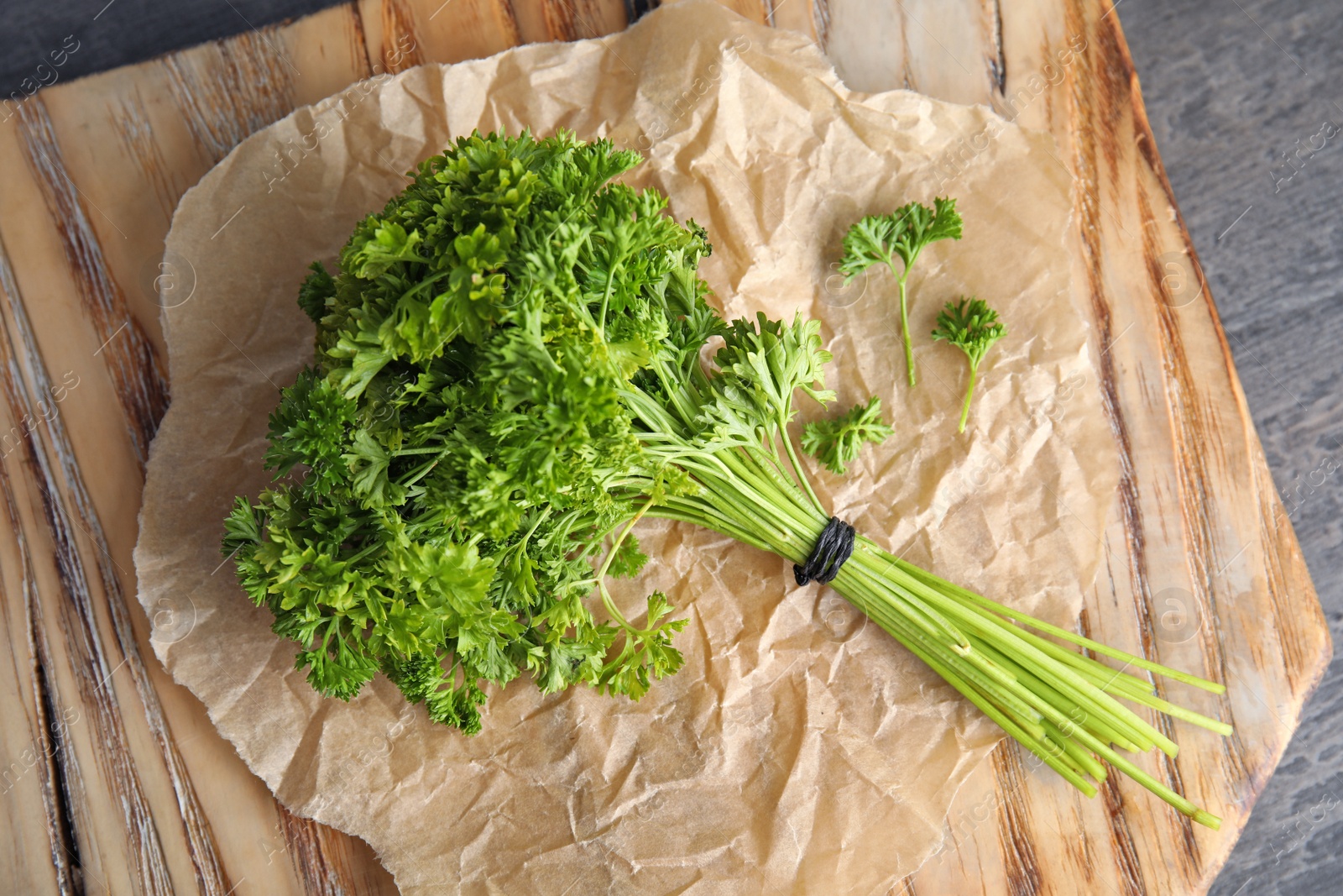 Photo of Wooden board with fresh green parsley on table, top view