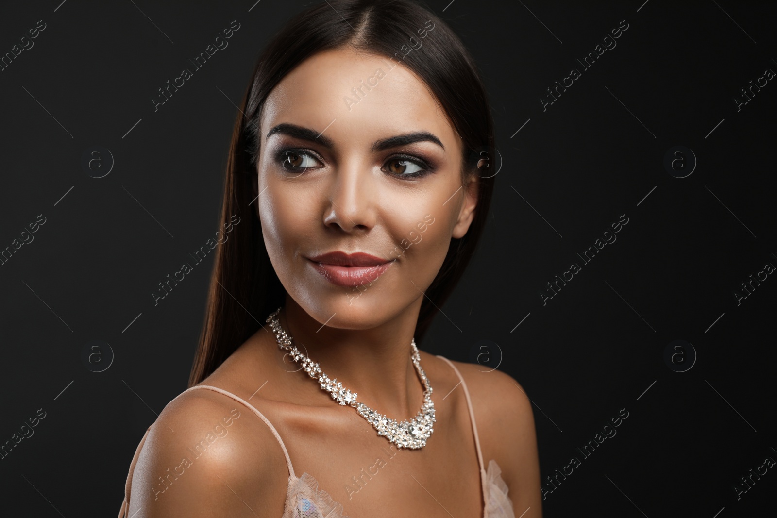 Photo of Beautiful young woman with elegant jewelry on dark background. Space for text