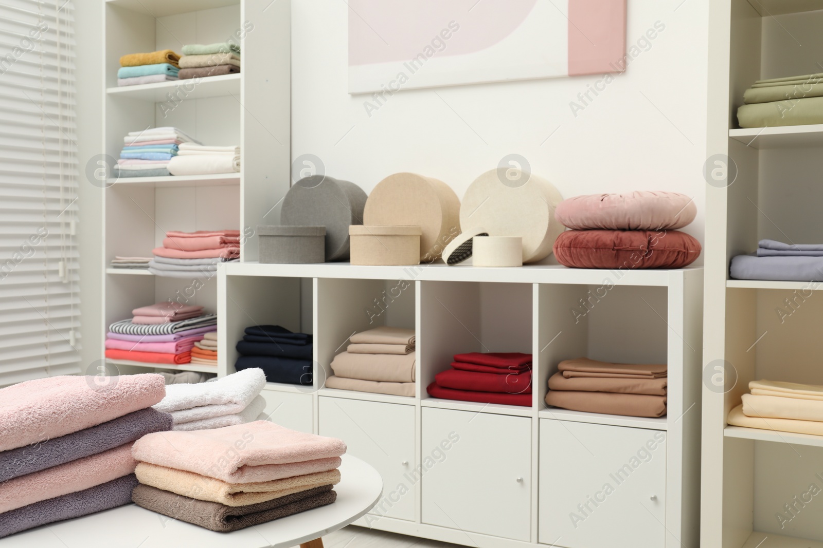 Photo of Different colorful bed linens and decorative boxes on display in home textiles store