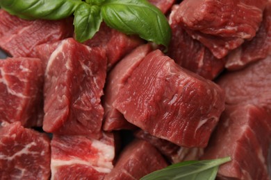 Photo of Cut fresh beef meat with basil leaves as background, closeup