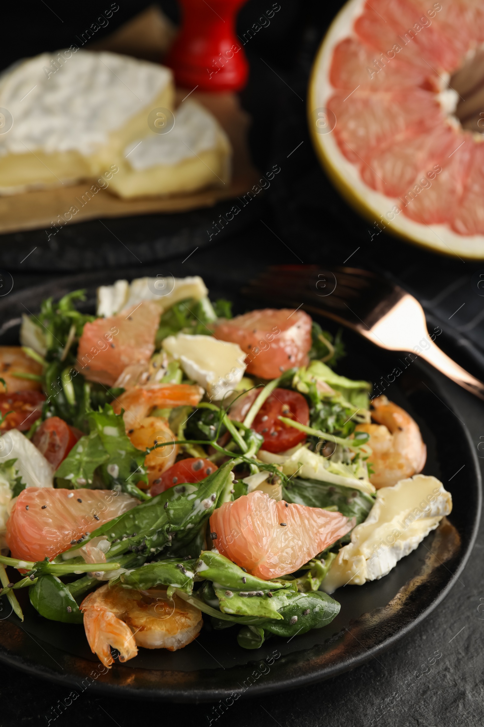 Photo of Delicious pomelo salad with shrimps served on black table, closeup