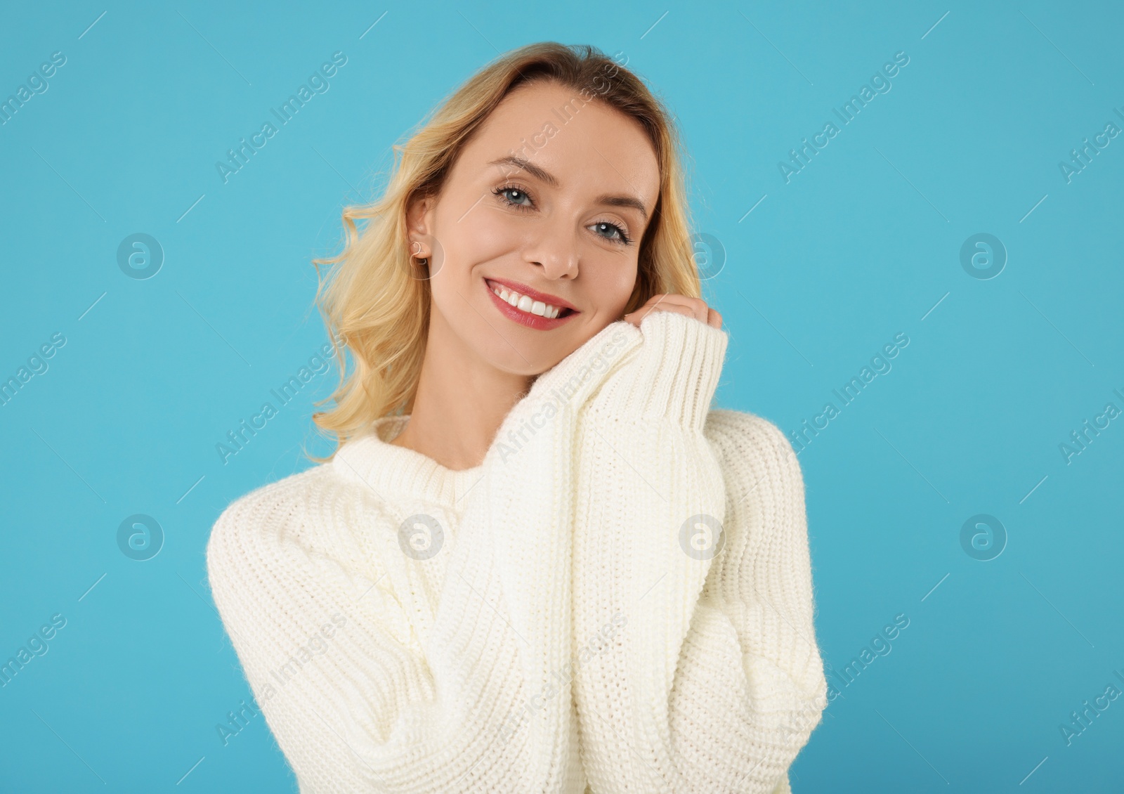 Photo of Happy woman in stylish warm sweater on light blue background