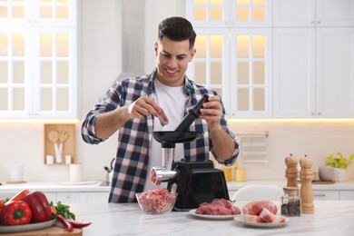 Photo of Man using modern meat grinder in kitchen