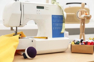 Sewing machine, tools and fabric on wooden table indoors, closeup