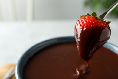 Photo of Dipping strawberry into fondue pot with chocolate, closeup. Space for text
