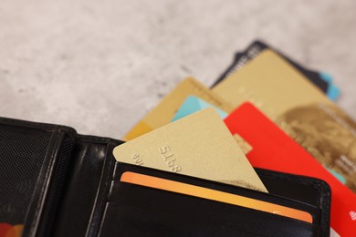 Many different credit cards and leather wallet on grey table, closeup