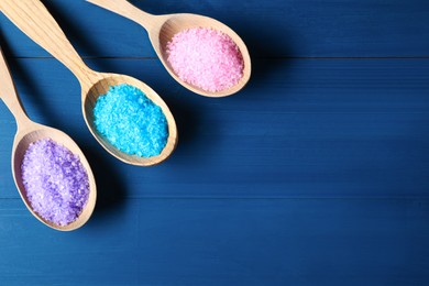 Photo of Spoons with colorful sea salt on blue wooden table, flat lay. Space for text