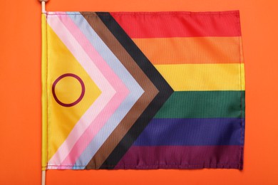 Photo of Bright progress flag on orange background, top view. LGBT pride
