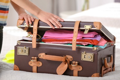 Woman packing suitcase for journey at home, closeup