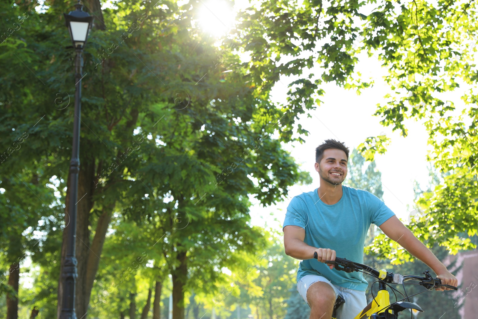 Photo of Handsome young man riding bicycle on city street, low angle view