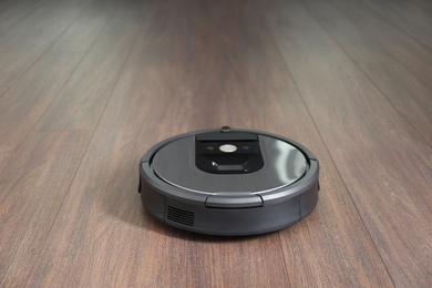 Photo of Modern robotic vacuum cleaner on wooden floor