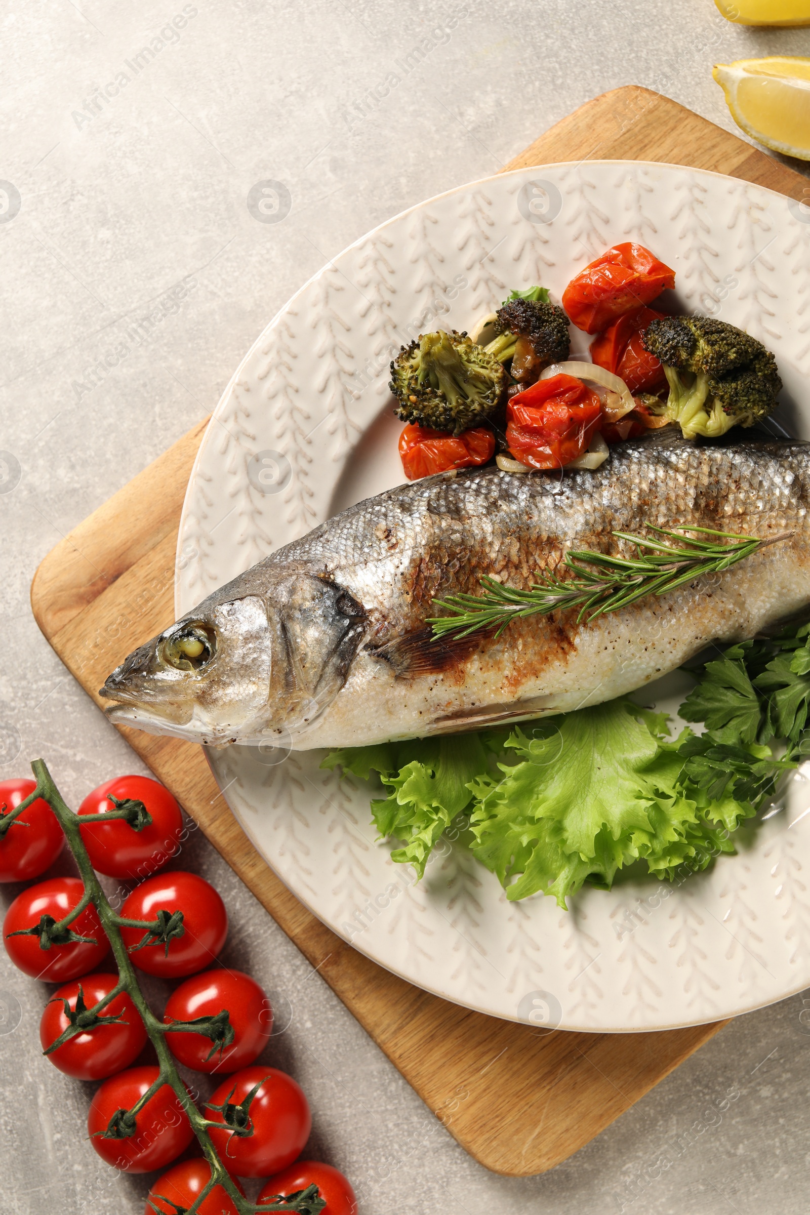 Photo of Delicious baked fish and vegetables on light grey table, top view