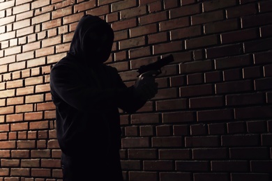 Photo of Man in hoodie with gun indoors. Dangerous criminal