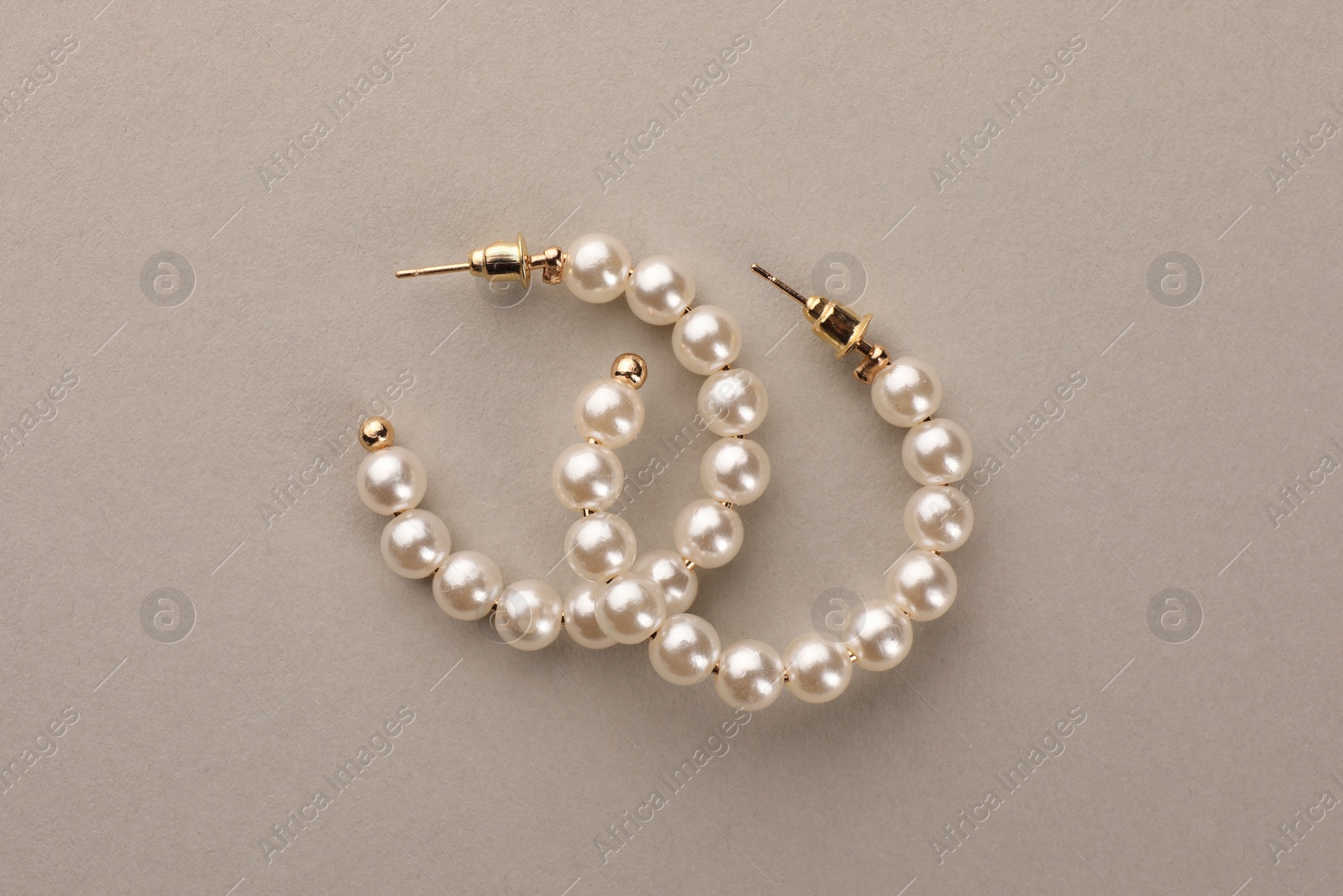 Photo of Elegant earrings with pearls on beige background, top view