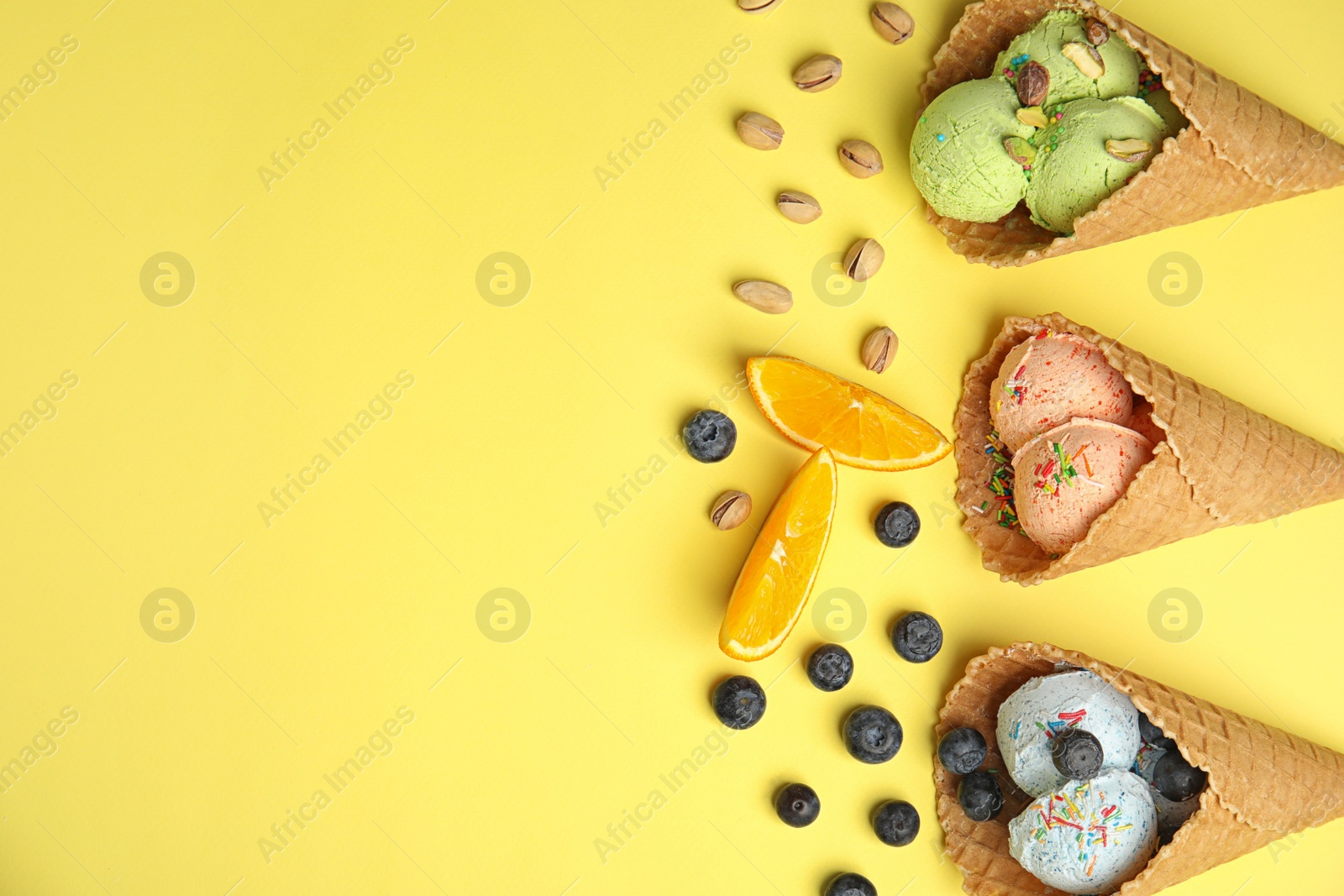 Photo of Flat lay composition with delicious ice creams in waffle cones on color background, space for text