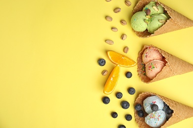 Flat lay composition with delicious ice creams in waffle cones on color background, space for text