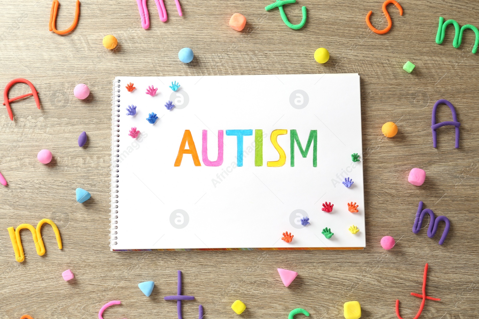 Photo of Flat lay composition of notebook with word Autism and plasticine on wooden table