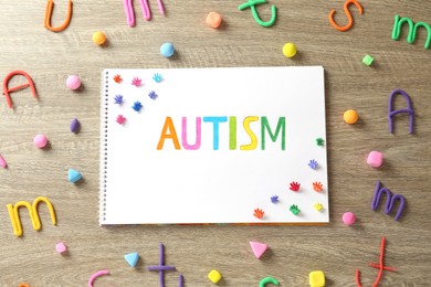 Flat lay composition of notebook with word Autism and plasticine on wooden table