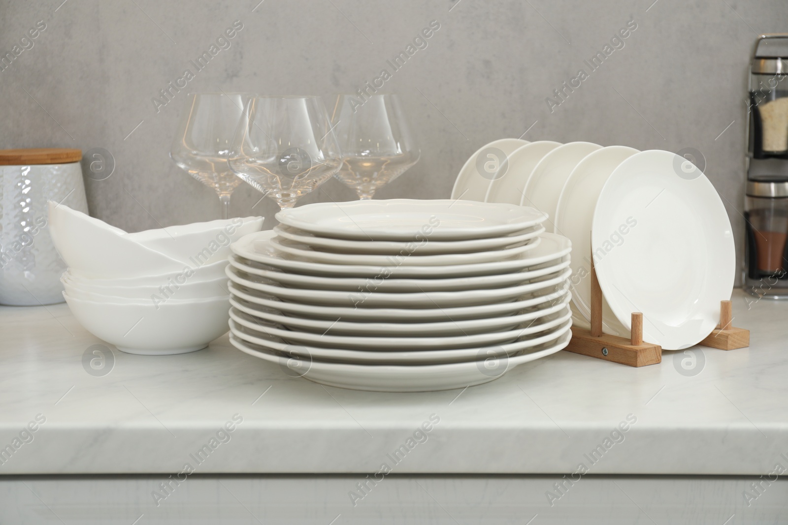 Photo of Clean plates, bowls and glasses on white marble table