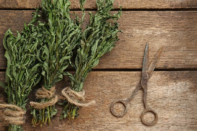 Photo of Bunches of wilted mint and old scissors on wooden table, flat lay