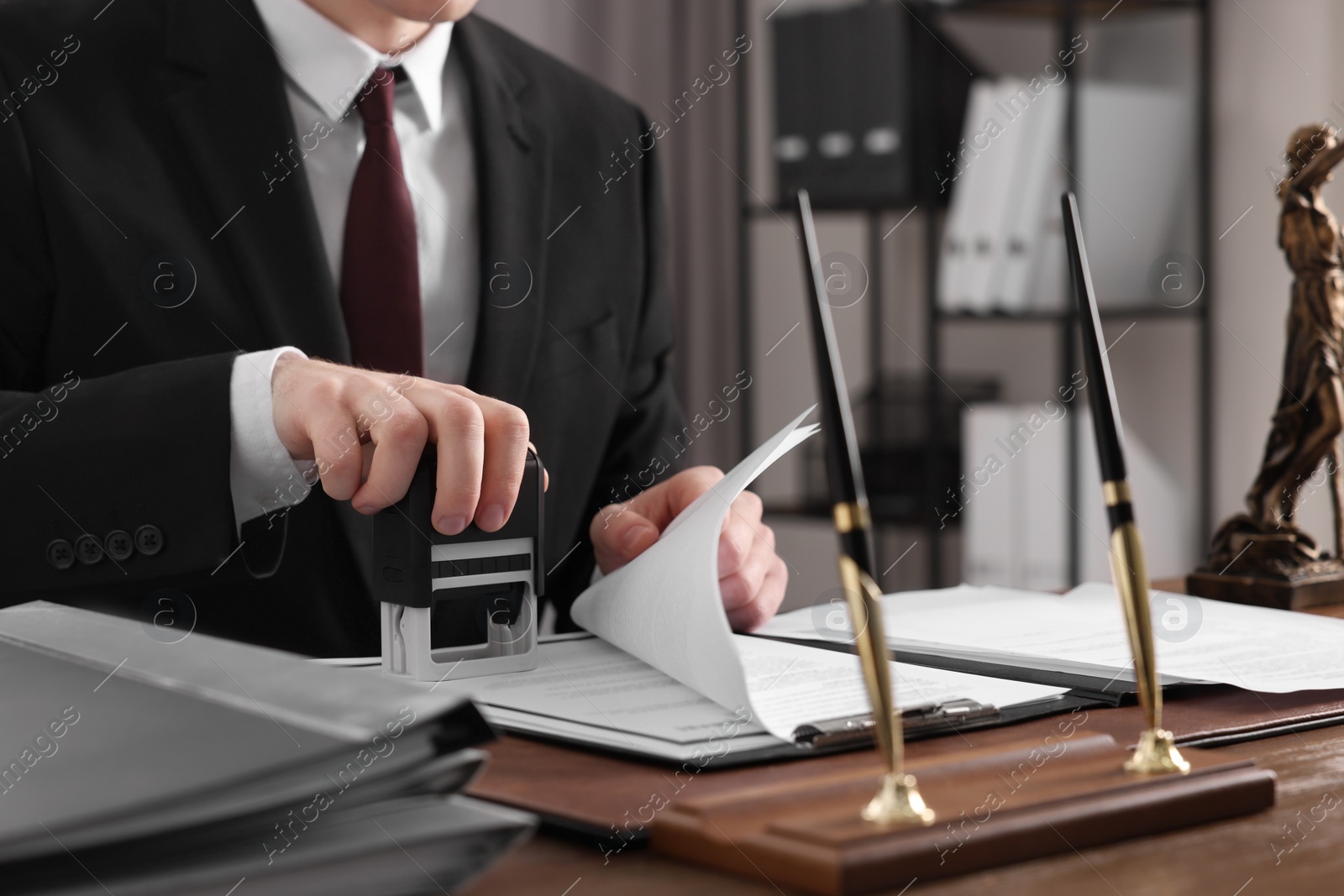 Photo of Notary stamping document at table in office, closeup