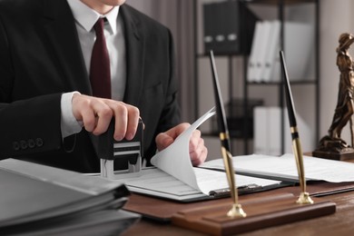 Notary stamping document at table in office, closeup