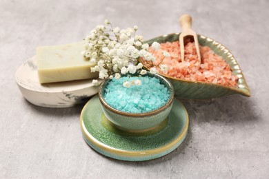Photo of Colorful sea salt and beautiful flowers on light grey table