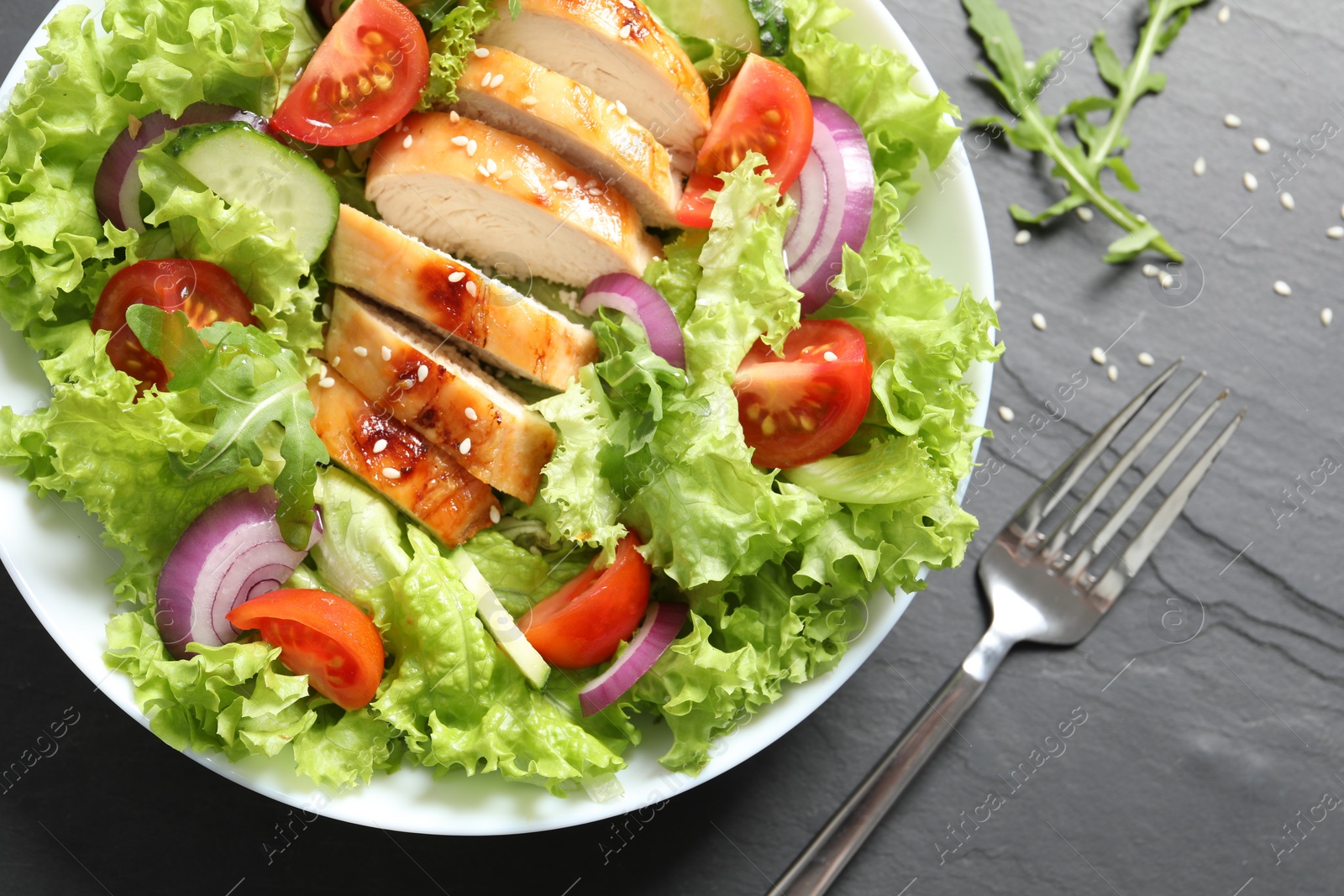 Photo of Delicious salad with chicken and vegetables served on black table, top view