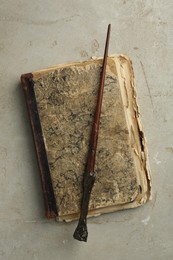 Photo of Magic wand and old book on light textured background, top view