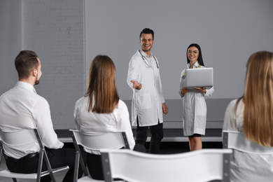 Young doctors with laptop giving lecture in conference room with projection screen