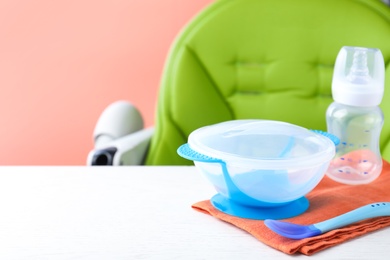 Photo of Set of plastic dishware on white wooden table. Serving baby food