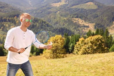 Photo of Man playing badminton in mountains on sunny day. Space for text