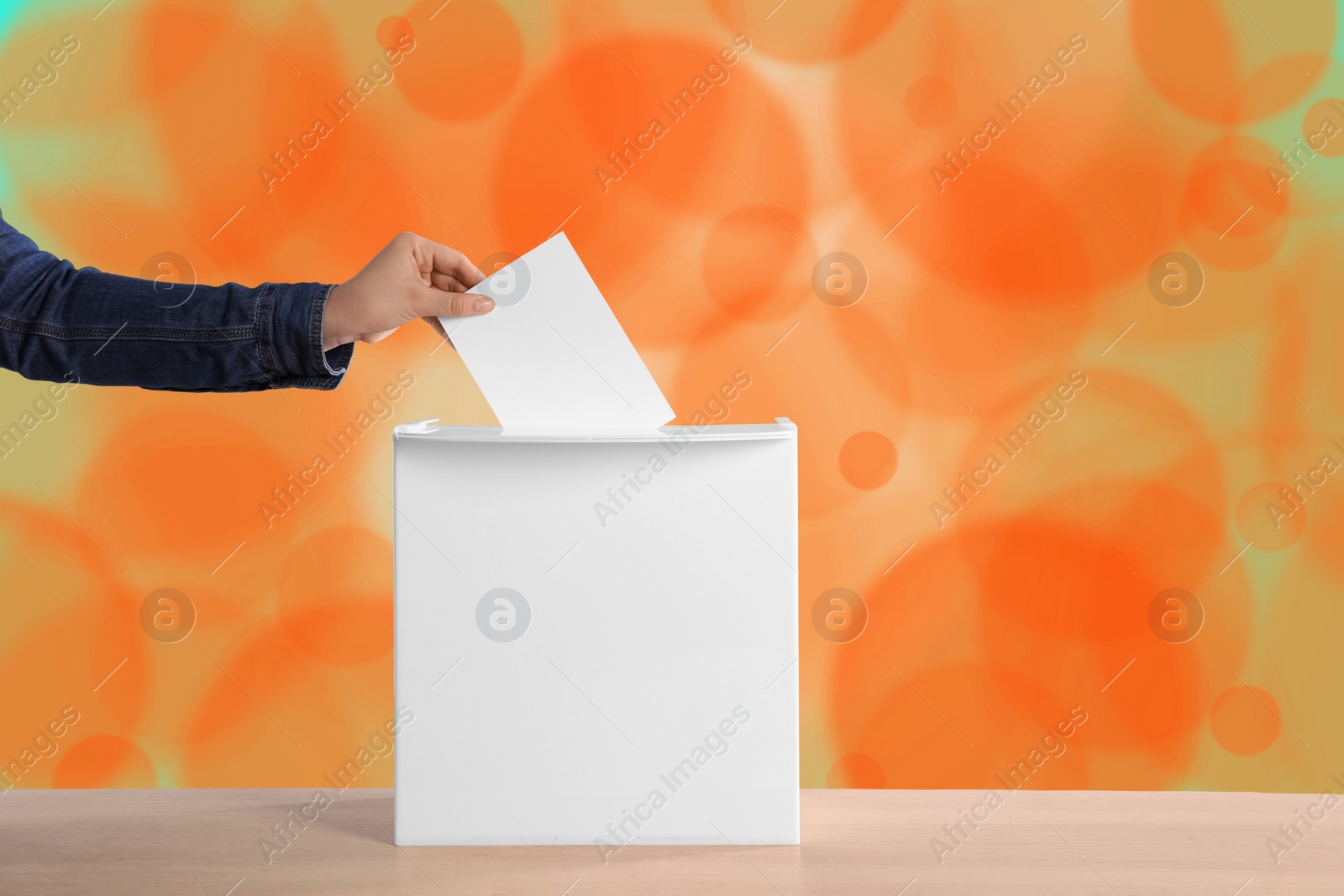 Image of Woman putting her vote into ballot box on color background, closeup