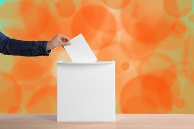 Woman putting her vote into ballot box on color background, closeup