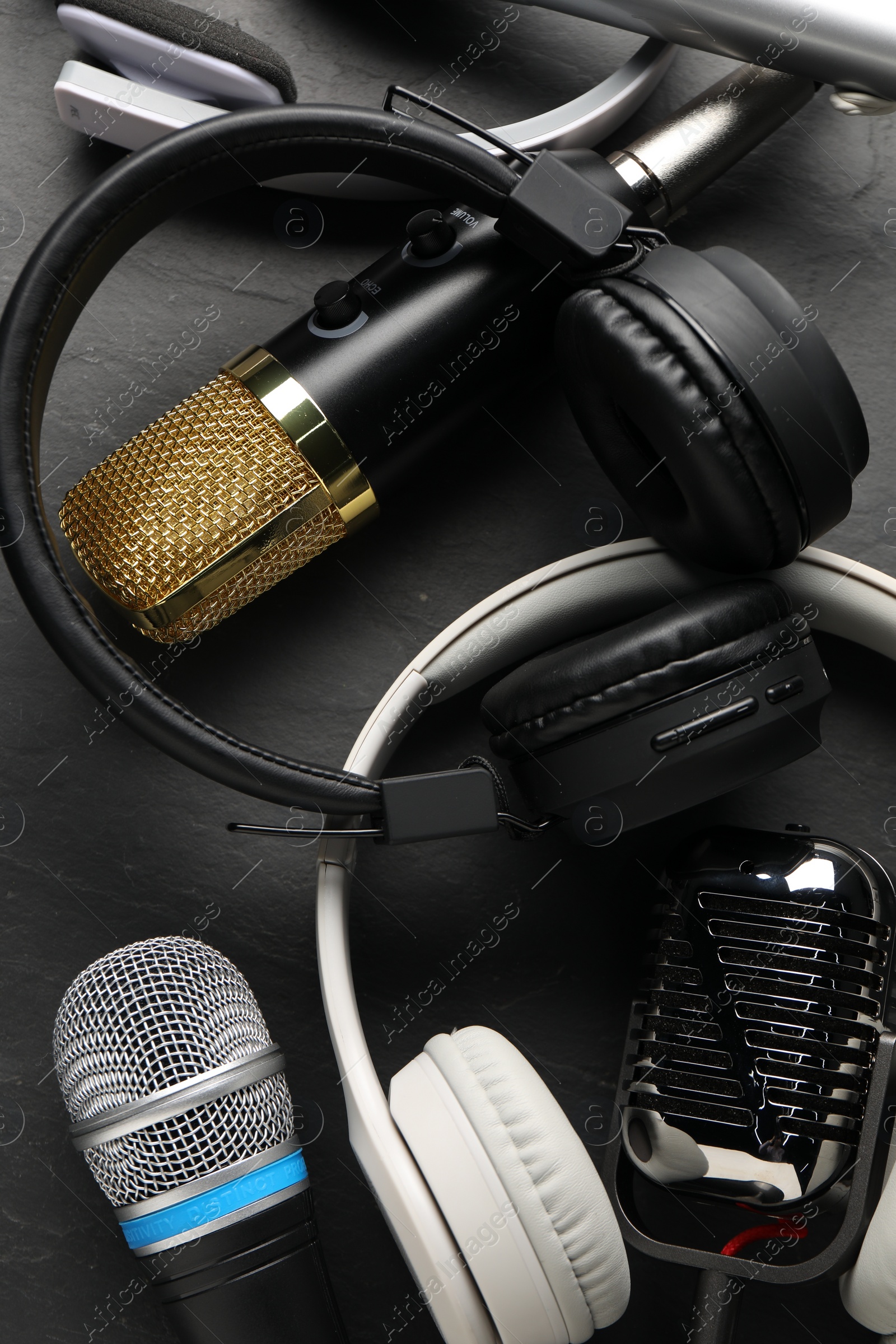 Photo of Different microphones and headphones on grey textured background, flat lay. Sound recording and reinforcement